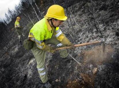 Dos agentes forestales repasan la superficie quemada para evitar que se reavive el fuego.