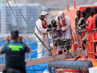 Dos rescatistas ayudaban el domingo a un migrante a desembarcar en el puerto de Arguineguín (Gran Canaria).