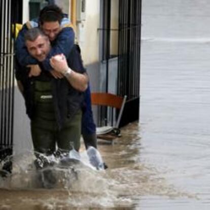 Un vecino de Lora del Río (Sevilla) lleva a cuestas a una mujer por una de las calles que aún continúan anegadas, debido a la crecida del río Guadalquivir.