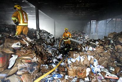 Los bomberos apagan los rescoldos de una de las naves propiedad de empresarios chinos incendiadas el jueves en Elche.