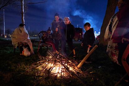 A group of residents gathers around a fire in an open field following a series of earthquakes.