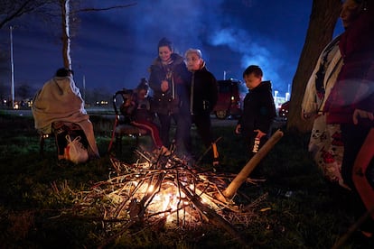 A group of residents gathers around a fire in an open field following a series of earthquakes.