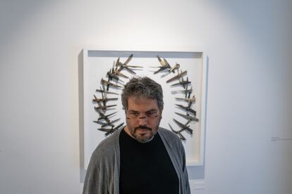 Rafael Londoño, curador de la exposición Contra-política, con la obra: Democracia, en el fondo, de Carlos Castro.