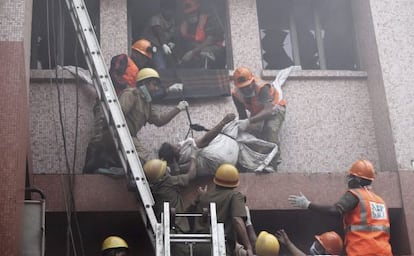 Trabajadores de los equipos de rescate evac&uacute;an el cuerpo sin vida de una paciente de un hospital de AMRI en Calcuta (India) tras un incendio