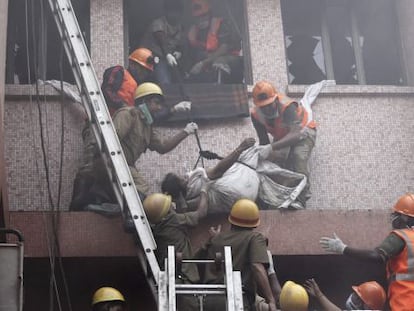 Trabajadores de los equipos de rescate evacúan el cuerpo sin vida de una paciente de un hospital de AMRI en Calcuta (India) tras un incendio