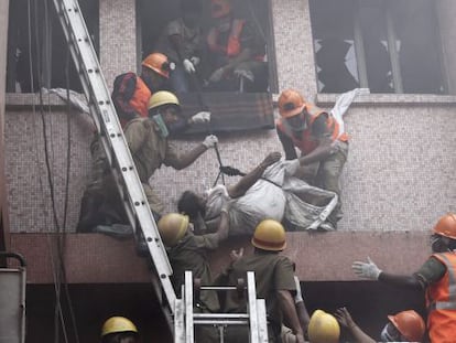 Trabajadores de los equipos de rescate evac&uacute;an el cuerpo sin vida de una paciente de un hospital de AMRI en Calcuta (India) tras un incendio