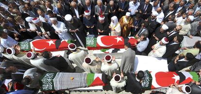 Los asistentes al funeral de las víctimas del asalto israelí rezan ante los féretros.