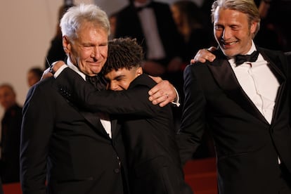 El joven actor francés Ethann Isidore abraza a la estrella de Hollywood Harrison Ford en presencia del actor danés Mads Mikkelsen, durante la premiere de la película 'Indiana Jones y el llamado del destino', el 18 de mayo.