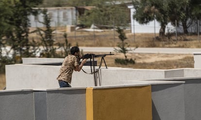 Un miembro de las brigadas leales al Gobierno de Unidad usa una ametralladora desde un tejado para dar fuego de cobertura durante el ataque al Aeropuerto Internacional de Trípoli.