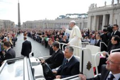 El papa Francisco saluda hoy a los miles de peregrinos que aguardan con paraguas bajo la lluvia para asistir a la audiencia general de todos los miércoles en la Plaza de San Pedro del Vaticano, en El Vaticano.