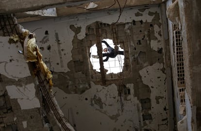 Un miembro del grupo practica parkour sobre el tejado de un edificio medio derruido tras un bombardeo.