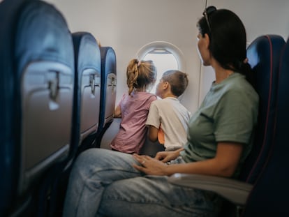 Dos niños mirando por la ventanilla de un avión.