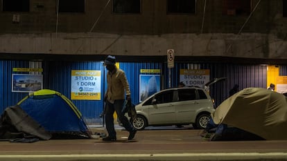 Um homem passa por barracas onde vivem moradores de rua no centro de São Paulo.