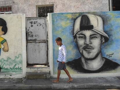 Menino caminha diante de grafites sobre a Copa no Rio.