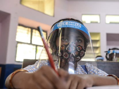 Una estudiante con mascarilla y plástico protector atiende en clase el 11 de febrero de 2022 en uno de los colegios públicos femeninos de Hyderabad, India.