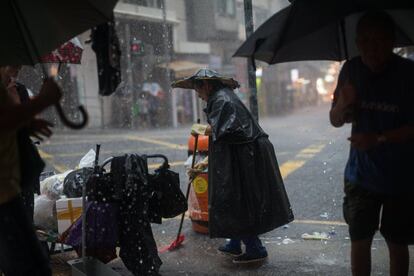Un trabajador barre una calle durante una tormenta torrencial en Hong Kong.