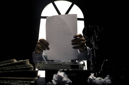 Un hombre coloca un folio en su máquina de escribir.