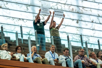 Dos asistentes muestran sendos carteles en protesta por la gestión de los incendios, durante la sesión de este viernes en las Cortes de Castilla y León.