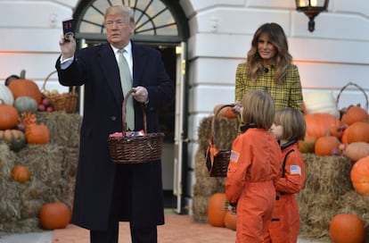 El presidente Donald Trump y la primera dama, Melania Trump, entregan una cesta con pequeños regalos y gominolas a dos niños disfrazados para Halloween.