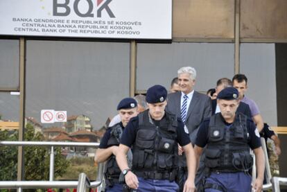 El gobernador del Banco Central de Kosovo, en el centro, es escoltado por agentes de policía tras su detención.