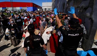 Una pareja de agentes del Cuerpo Nacional de Policía da instrucciones al grupo de 200 marroquíes que hacen  cola para poder pasar a Marruecos a través del paso fronterizo de Beni-Enzar de Melilla.  