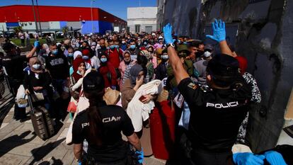 Una pareja de agentes del Cuerpo Nacional de Policía da instrucciones al grupo de 200 marroquíes que hacen  cola para poder pasar a Marruecos a través del paso fronterizo de Beni-Enzar de Melilla.  