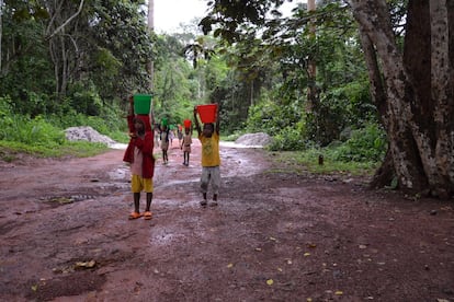 Niños con cubos llenos de agua regresan de la fuente antes de lavarse por la mañana temprano. Muchos vecinos bantúes, con los que conviven los bakas, no los consideran personas y, por tanto, creen que no tienen derecho a la educación. Pero también es verdad que muchos padres pigmeos se llevaban a sus hijos a la selva a cazar, pescar o recolectar, por lo que los pequeños se ausentaban de las aulas durante semanas. Para combatir estos dos males se optó por abrir el Hogar Infantil con una zona para chicas y otra para chicos.