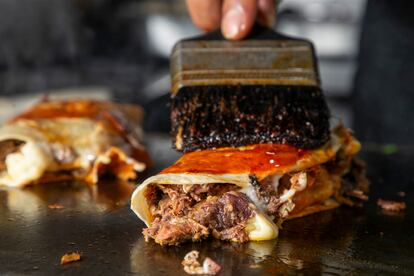 Un taquero prepara una quesabirria.