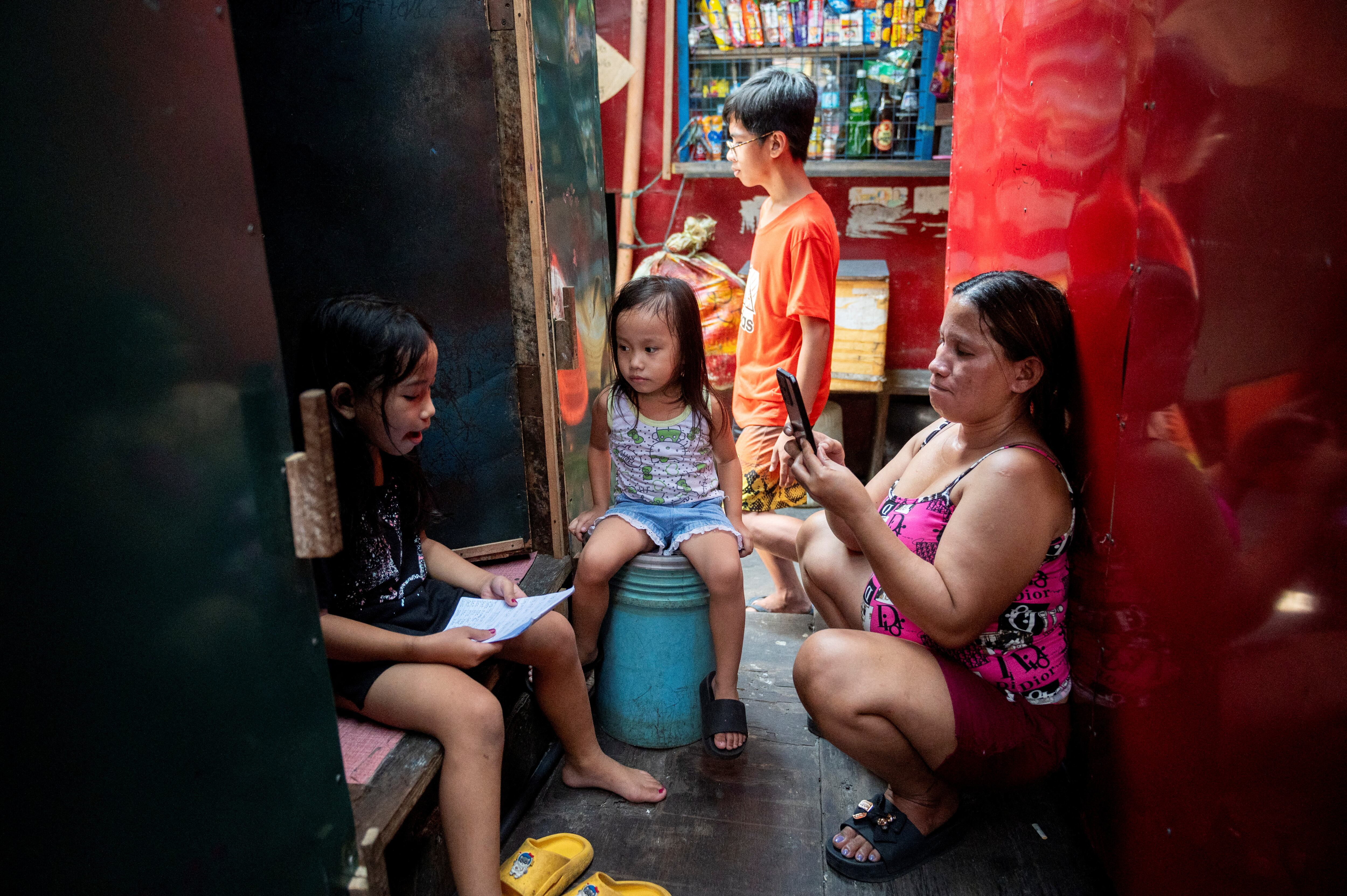 Una mujer grababa el viernes a su hija completando un ejercicio de lectura fuera de su casa en Manila. 