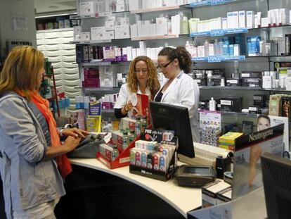 Dos empleadas de la farmacia licenciada Elena Timpanaro, en Bilbao, atienden a una clienta. 