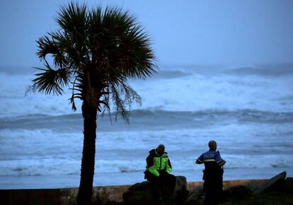 Dos agentes de la policía de Daytona Beach patrullan la playa mientras las fuertes olas del huracán golpean la costa.