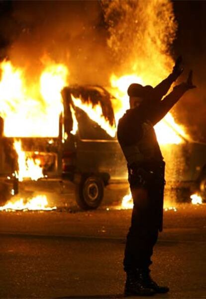 Un policía francés gesticula frente a un coche incendiado durante los disturbios de anoche en Estrasburgo.