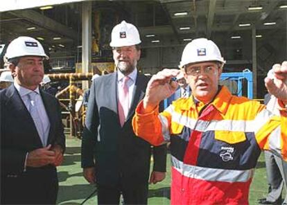 Mariano Rajoy, al centro, y Alfonso Cortina, escuchan las explicaciones sobre la extracción de fuel de un empleado de Repsol.