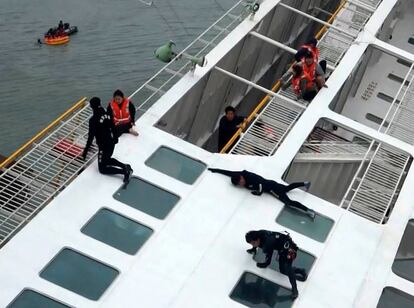 Agentes marítimos, vestidos de negro, tratan de rescatar a unos pasajeros del "Sewol", que se hundió frente a Jindo (Corea del Sur).