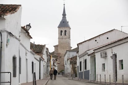 Dos hombres caminan por Torres de la Alameda en direcci&oacute;n a la iglesia.