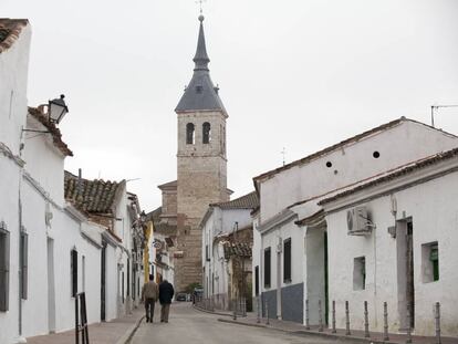 Dos hombres caminan por Torres de la Alameda en direcci&oacute;n a la iglesia.