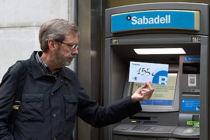 El llamamiento hecho por Crida per la Democràcia, plataforma vinculada a Òmnium Cultural y la Asamblea Nacional Catalana (ANC), a retirar dinero en efectivo de los cinco principales bancos nacionales ha tenido una escasa acogida, según han explicado fuentes financieras. En la imagen, un usuario de banca muestra la cantidad de dinero que ha retirado de un cajero en la ciudad de Barcelona.