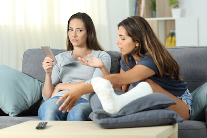 Angry woman ignoring her roommate sitting on a couch in the living room at home