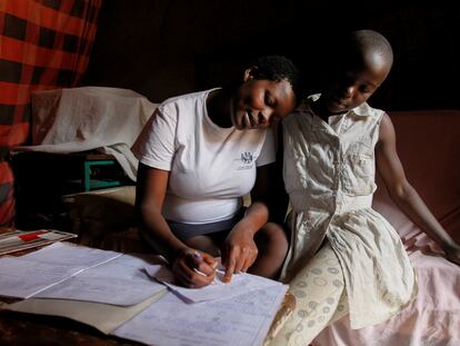 Jackline Bosibori, de 17 años, ayuda a su hermana Angela, de 12, con los deberes del colegio, en su casa del barrio de Kibera, en Kenia. En esta imagen, de septiembre de 2020, la adolescente estaba embarazada de siete meses.