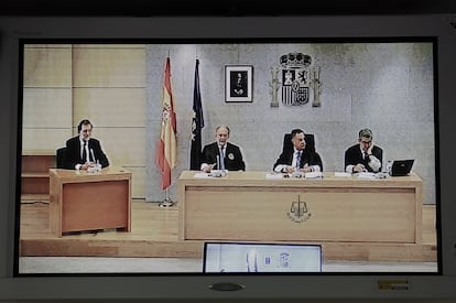 Imagen de un monitor de la sala de prensa de la Audiencia Nacional, donde se ve a Rajoy a la izquierda, durante su declaración como testigo en el juicio del 'caso Gürtel', en 2017.