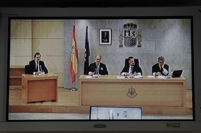 Imagen de un monitor de la sala de prensa de la Audiencia Nacional, donde se ve a Rajoy a la izquierda, durante su declaración como testigo en el juicio del 'caso Gürtel', en 2017.