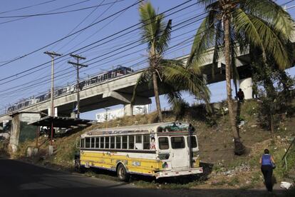 El metro pasa por un viaducto edificado sobre uno de los barrios de la perifería de la ciudad de Panamá, donde los vecinos han bautizado a este autobús abandonado como El Diablo Rojo.