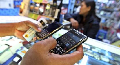 Un cliente sostiene dos tel&eacute;fonos m&oacute;viles BlackBerry 