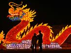 People talk in front of a giant dragon lantern in a park in Wuhan in China's central Hubei province on February 11, 2021, ahead of the start of the Lunar New Year, which ushers in the Year of the Ox on February 12. (Photo by Hector RETAMAL / AFP)