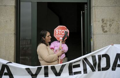 María del Pilar López sostiene a su hija Carolina, en el portal de su casa en Ourense. La plataforma Stop Desahucios logró frenar su desalojo por impago del alquiler.