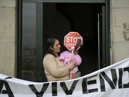 María del Pilar López sostiene a su hija Carolina, en el portal de su casa en Ourense. La plataforma Stop Desahucios logró frenar su desalojo por impago del alquiler.