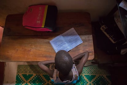 Leticia Amongin, de oito anos, faz a lição de casa com a pouca luz que entra pela janela de sua casa em Uganda.