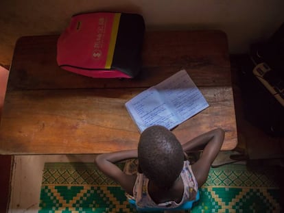 Leticia Amongin, de oito anos, faz a lição de casa com a pouca luz que entra pela janela de sua casa em Uganda.