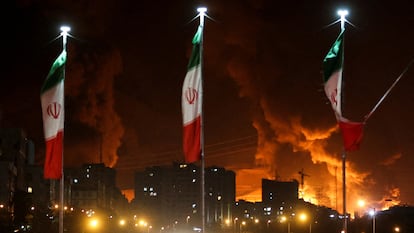 Banderas iraníes frente a un depósito de petróleo atacado por Israel, el 15 de junio de 2025.