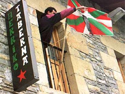 Un simpatizante de HB coloca una <i>ikurriña</i> en la <i>herriko taberna</i> de Mallabia tras la muerte de un etarra en 1997.
